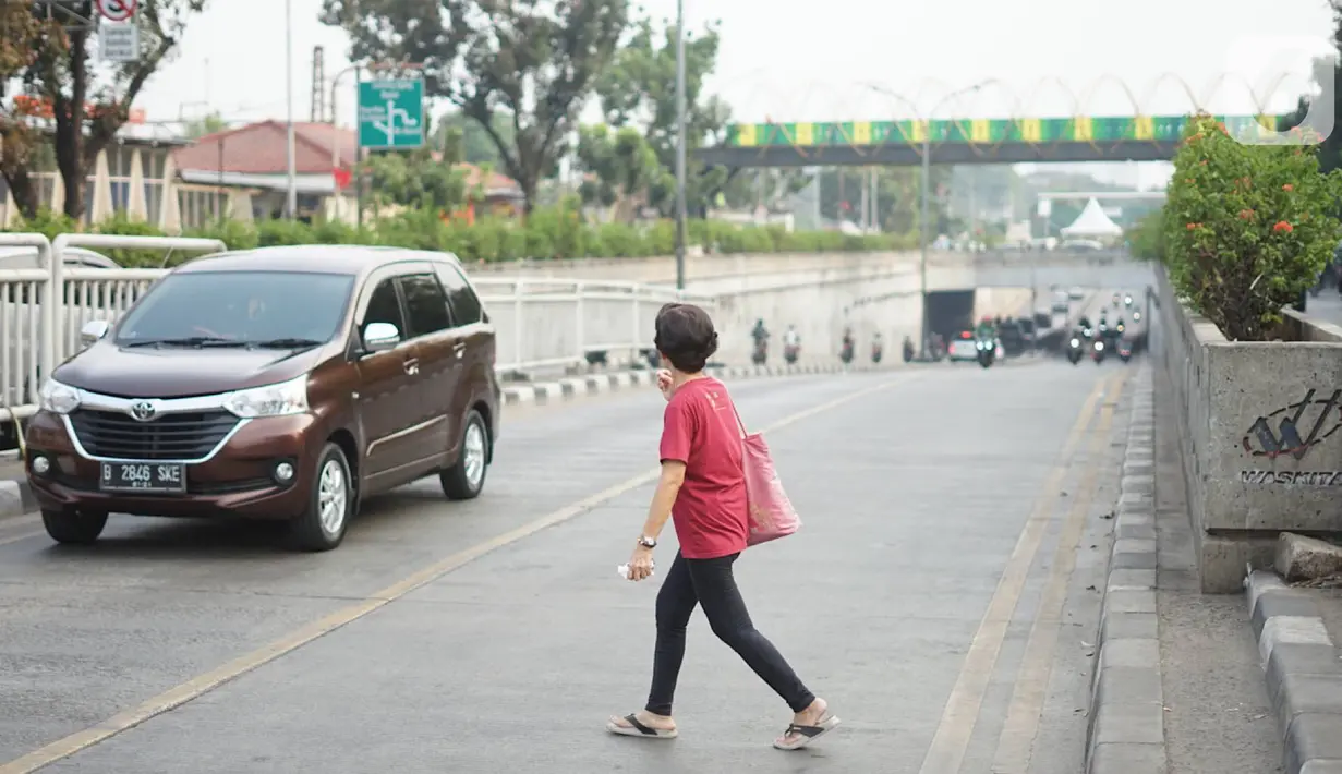 Warga menyeberang jalan di depan Stasiun Pasar Minggu, Jakarta, Rabu (16/10/2019). Jauhnya jembatan penyeberangan orang (JPO) membuat warga memanfaatkan celah pagar pembatas tersebut sebagai akses menyeberang, meski berbahaya bagi keselamatan. (Liputan6.com/Immanuel Antonius)