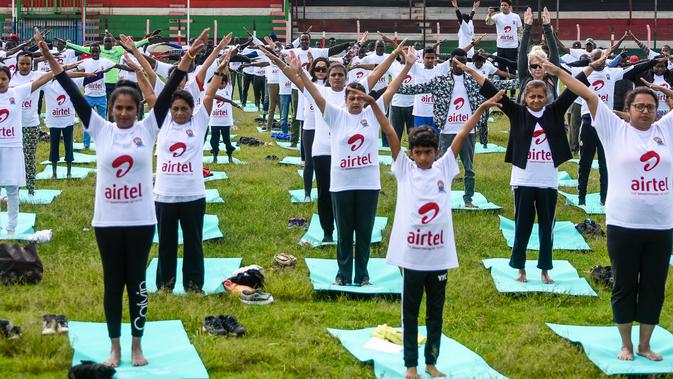 Ratusan warga melakukan gerakan yoga saat mengikuti sesi yoga massal di Stadion Afraha di Nakuru, Kenya (15/6/2019). Acara yoga massal ini untuk memperingati Hari Yoga Internasional. (AFP Photo/Suleiman Mbatiah)