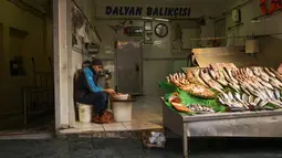 Seorang penjual ikan mengupas udang saat menunggu pembeli di pasar jalanan di Istanbul, Turki, Senin (3/1/2022). Inflasi tahunan Turki naik dengan laju tercepat dalam 19 tahun, melonjak menjadi 36,08% pada Desember lalu, menurut data resmi pada Senin. (AP Photo/Francisco Seco)