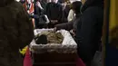 Ibu dari tentara Simakov Oleksandr (41) membelai wajah sang anak saat upacara pemakamannya, setelah dia meninggal dalam aksi, di Gereja Rasul Suci Petrus dan Paulus di Lviv, Ukraina barat, Senin, 4 April 2022. (AP Photo /Nariman El-Mofty)