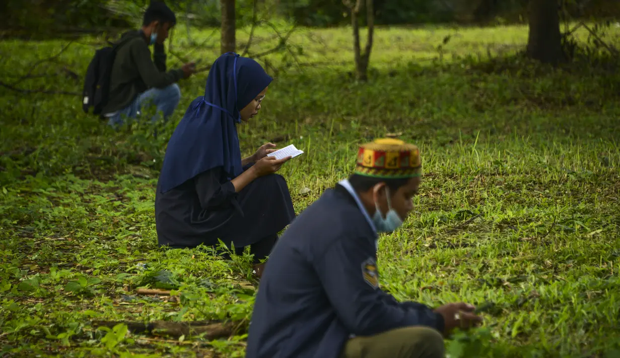 Orang-orang berdoa saat melakukan ziarah pada peringatan 16 tahun gempa bumi dan tsunami Aceh di sebuah kuburan massal di Siron, Sabtu (26/12/2020).  Peringatan di tengah pandemi COVID-19 itu tetap berlangsung secara sederhana melalui kegiatan ziarah kubur. (CHAIDEER MAHYUDDIN/AFP)