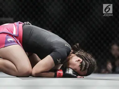 Petarung putri Indonesia, Priscilla Hertati Lumban Gaol sujud syukur usai mengalahkan Petarung putri Malaysia, Audreylaura Boniface saat berlaga pada partai pertama One Championship di Jakarta, Sabtu (20/1). (Liputan6.com/Faizal Fanani)