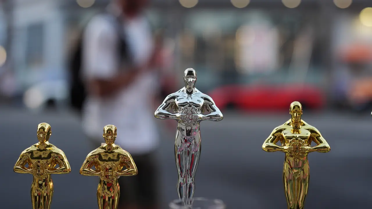 Seorang pria melewati replika patung Oscar pada hari Sabtu, 14 Maret 2026, di jalan dekat Dolby Theatre di Los Angeles, tempat persiapan terus berlangsung untuk upacara Academy Awards ke-98 pada hari Minggu. (AP Photo/Gregory Bull)