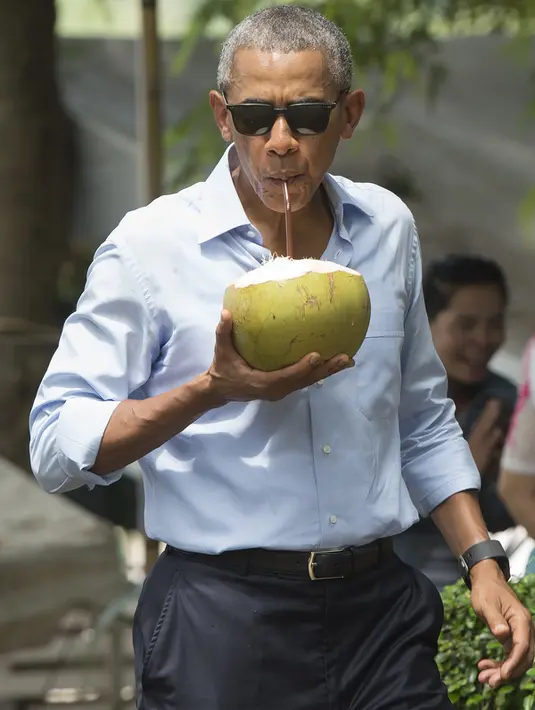 Barack Obama saat asik menyeruput air kelapa di sepanjang Sungai Mekong di Luang Prabang, Laos (7/9). Obama akan melakukan pertemuan bersama para pemimpin negara di KTT-ASEAN. (AFP PHOTO/SAUL Loeb)