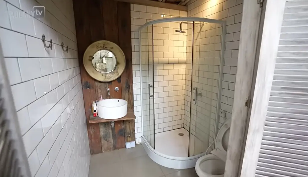 Kamar mandi tampak unik dengan pintu kayu model lama. Sedangkan sebagian dinding menggunakan kayu tebal bekas kapal. [YouTube/TAULANY TV]