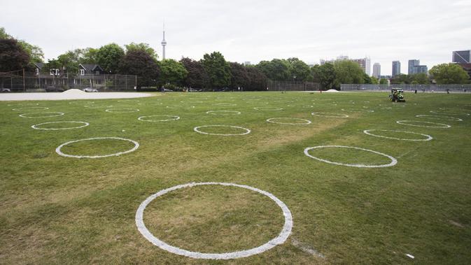 Sejumlah lingkaran putih terlihat di Taman Trinity Bellwoods, Toronto, Kanada, Kamis (28/5/2020). Taman Trinity Bellwoods digambari lingkaran-lingkaran putih sebagai proyek uji coba untuk mendorong warga melakukan jaga jarak fisik (physical distancing) selama pandemi COVID-19. (Xinhua/Zou Zheng)