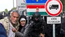 Dua imigran menyelamatkan diri dari polisi dengan imigran yang berusaha menerobos pintu perbatasan antara Serbia dan Hungaria di Roszke, Rabu (16/9/2015). (REUTERS/Marko Djurica)