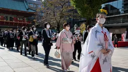 Pemilik robot anjing "aibo" mengikuti seorang gadis kuil (kanan) saat mereka melanjutkan ke aula kuil untuk menandai Festival Shichi-Go-San di Kuil Kanda Myojin, Tokyo, Jepang, Jumat (11/11/2022). Lebih dari 60 pemilik "aibo" menghadiri acara tradisional yang diadakan setiap tahun dengan mendoakan kesehatan yang baik di masa depan untuk anak perempuan berusia tiga dan tujuh tahun dan anak laki-laki berusia lima tahun. (Richard A. Brooks / AFP)