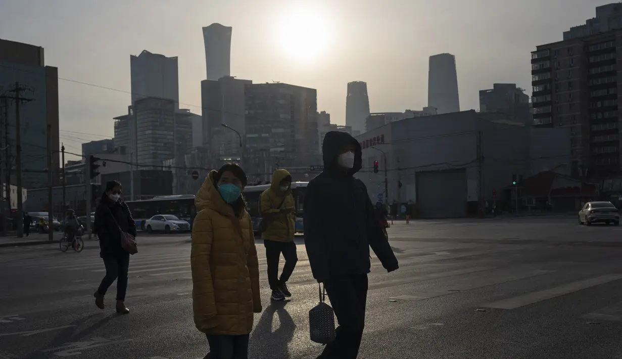 Warga yang memakai masker melintasi persimpangan di Beijing, China, Jumat (2/12/2022). Lebih banyak kota melonggarkan pembatasan, memungkinkan pusat perbelanjaan, supermarket, dan bisnis lainnya dibuka kembali menyusul protes akhir pekan lalu di Shanghai dan daerah lain di mana beberapa orang menyerukan Presiden Xi Jinping untuk mengundurkan diri. (AP Photo/Ng Han Guan)
