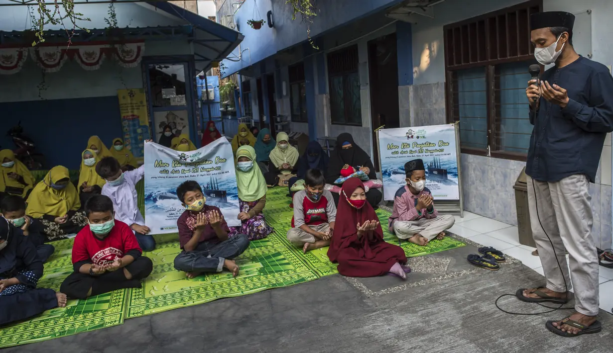Siswa dan guru berdoa untuk 53 awak kapal selam KRI Nanggala 402 yang hilang hilang kontak, di sebuah sekolah Islam di Surabaya, Jumat (24/4/2021). Kapal selam KRI Nanggala-402 hilang kontak saat sedang melaksanakan latihan penembakan dengan torpedo di perairan utara Pulau Bali. (Juni Kriswanto/AFP)