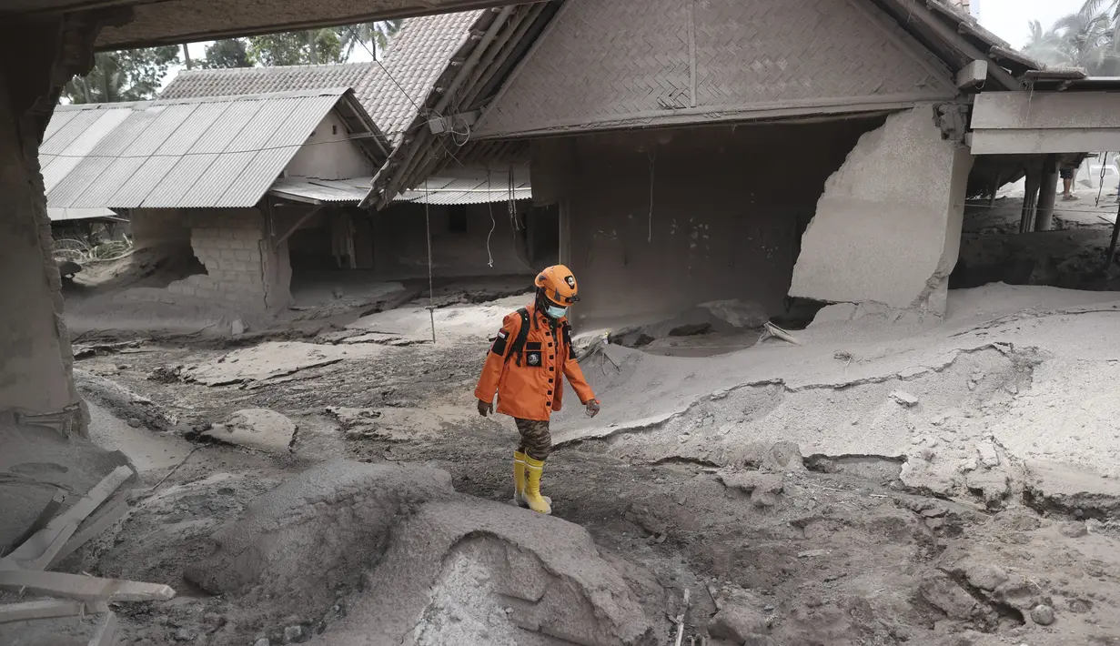Seorang tim penyelamat berjalan di daerah yang dilanda letusan Gunung Semeru di Kabupaten Lumajang, Provinsi Jawa Timur, Minggu (5/12/2021). BNPB menyatakan, korban meninggal akibat Gunung Semeru meletus mencapai 13 orang. Sementara 41 orang yang mengalami luka-luka. (AP Photo/Trisnadi)