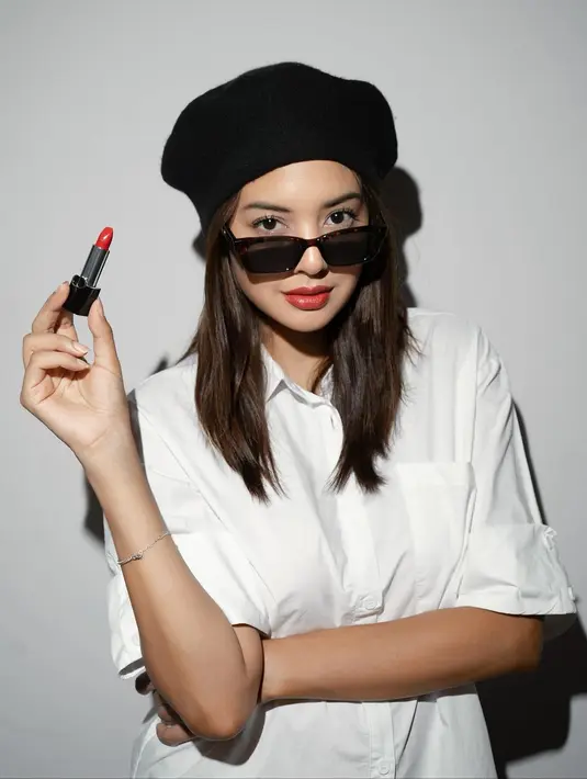 Gaya Parisian chic ala Aurelie Moeremans yang sangat pas dengan parasnya. Ia mengenakan kemeja putih lengan sesiku, topi hitam, sunglasses, dan memulas bibirnya dengan lipstick merah merona. [Foto: Instagram/aurelie]