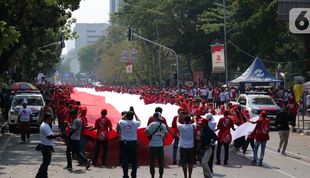 Sejumlah relawan membentangkan Bendera Merah Putih di kawasan jalan Medan Merdeka Selatan, Jakarta, Minggu (20/10/2019). Bendera Merah Putih Sekitar 200 meter dibentangkan jelang pelantikan Presiden-Wapres RI terpilih Joko Widodo-Ma'ruf Amin periode 2019-2024. (Liputan6.com/Herman Zakharia)