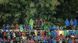 Sejumlah pendukung tuan rumah menggunakan jas hujan saat menyaksikan laga leg kedua final Pegadaian Liga 2 2023/2024 antara Semen Padang menghadapi PSBS Biak di Stadion GOR Haji Agus Salim, Padang, Sabtu (9/3/2024). (Bola.com/Bagaskara Lazuardi)