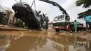 Orang-orang berusaha mengeluarkan mobil yang hanyut oleh air banjir di jalan yang terkena banjir bandang setelah hujan deras di Trademoore Estate, Lugbe, Abuja, Nigeria (13/9/2021). (AFP/Kola Sulaimon)