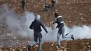 Pengunjuk rasa Palestina menggunakan ketapel untuk melemparkan batu ke arah pasukan Israel selama protes terhadap pemukiman Israel, di desa Deir Jarir Tepi Barat, utara Ramallah, Jumat (1/1/2021). (AP Photo/Majdi Mohammed)