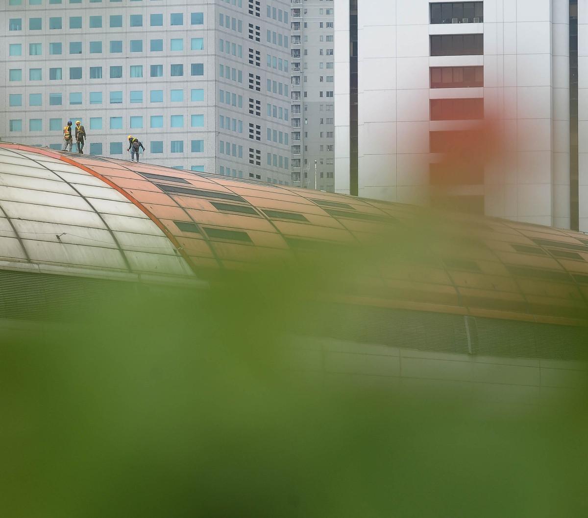 Pekerja beraktivitas saat melakukan pengecekan pada atap Halte LRT Jabodebek di Stasiun Dukuh Atas, Jakarta, Senin (19/2/2024). Foto merdeka.com / Imam Buhori