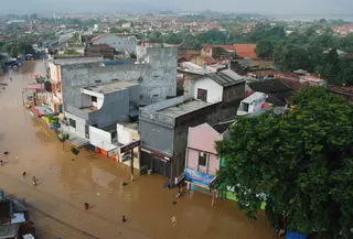 Sejumlah warga melintasi genangan banjir untuk mengungsi di jalan Raya Dayeuhkolot, Kabupaten Bandung, Minggu (13/3). Kawasan Bandung Selatan kembali dilanda banjir akibat luapan Sungai Citarum dan membuat ribuan orang mengungsi. (Timur Matahari/AFP)