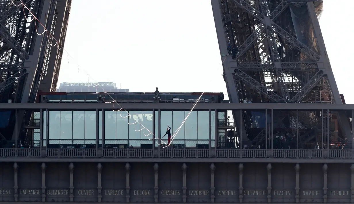 Aksi menegangkan seniman trapeze, Nathan Paulin saat berjalan di seutas tali dari Menara Eiffel menuju alun-alun Trocadero, Paris, 9 Desember 2017. Pria 22 tahun itu melakukan penyeberangan sejauh 2.198 kaki di atas Sungai Seine. (JACQUES DEMARTHON/AFP)