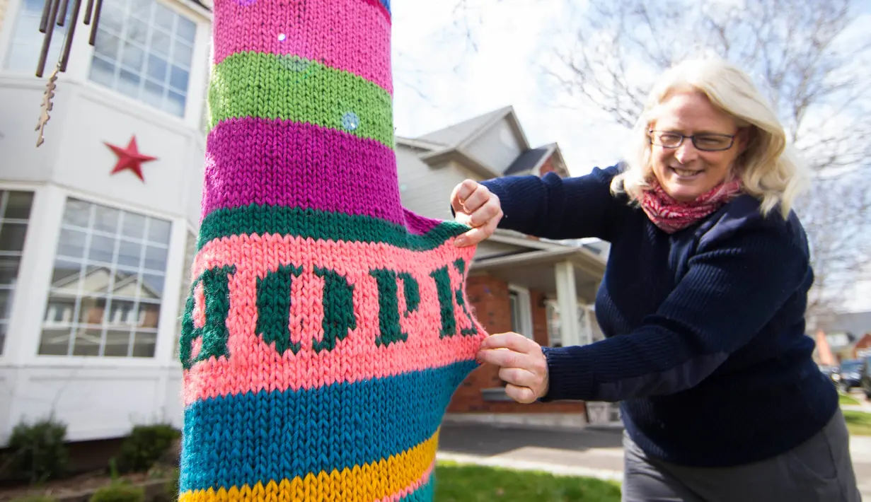 Seorang warga menunjukkan kata "Harapan" pada pohon yang dibalut rajutan benang di Burlington, Ontario, Kanada, (19/4/2020). Hingga Minggu (19/4) siang waktu setempat, sebanyak 34.813 kasus infeksi COVID-19 dan 1.583 kematian akibat penyakit tersebut dilaporkan di negara itu. (Xinhua/Zou Zheng)