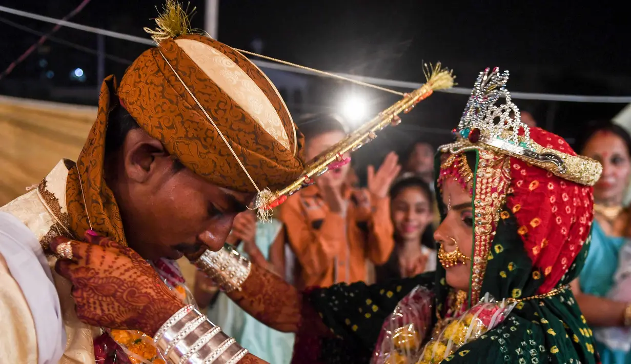 Sepasang pengantin menjalani ritual dalam prosesi pernikahan massal umat Hindu di Karachi, Pakistan, (19/3). Sebanyak 62 pasangan pengantin mengikuti pernikahan massal yang merupakan bagian dari perayaan Festival Holi. (AFP Photo /Asif Hassan)