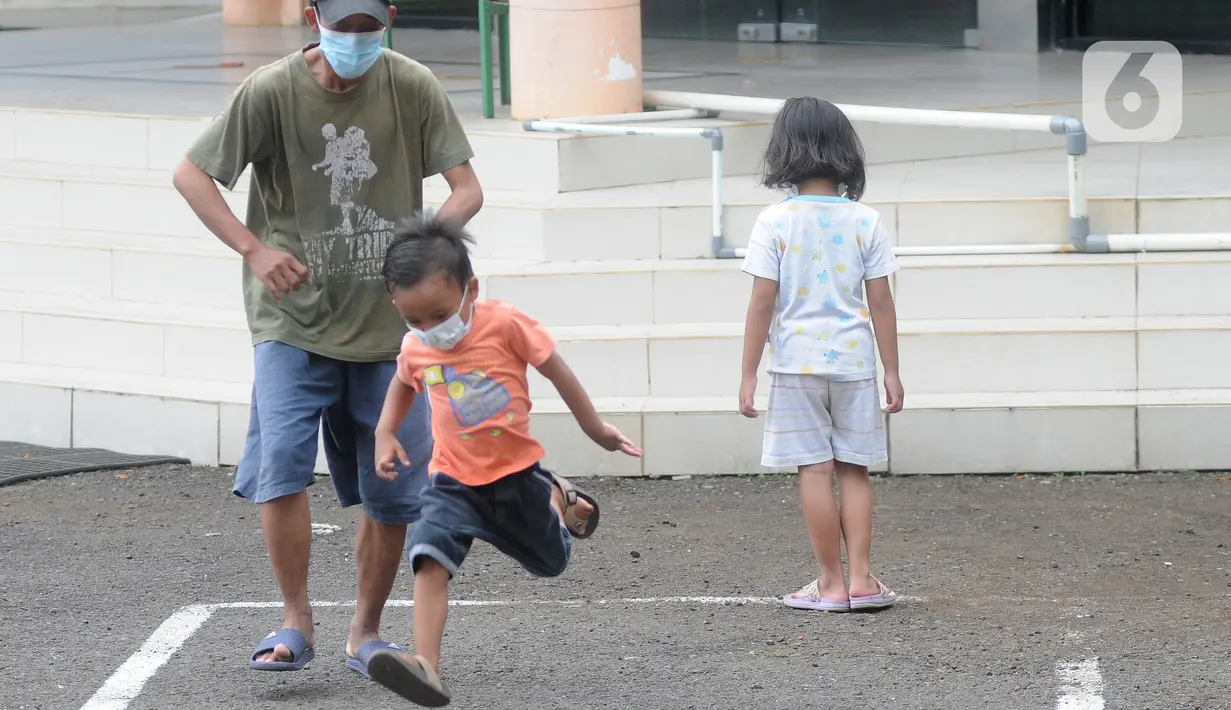 Pasien Covid-19 menemani seorang anak bermain di halaman Graha Wisata Ragunan, Jakarta, Selasa (15/6/2021). Pemprov DKI memfungsikan kembali Graha Wisata Ragunan sebagai tempat isolasi warga terpapar COVID-19 kategori OTG sejak pekan lalu dan saat ini merawat 117 pasien. (merdeka.com/Arie Basuki)