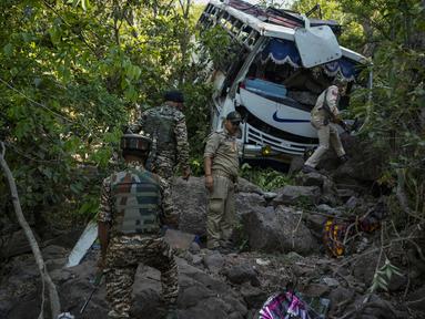 Petugas keamanan memeriksa sebuah bus yang jatuh ke jurang yang dalam pada hari Minggu setelah ditembaki oleh kelompok militan di distrik Reasi, Jammu dan Kashmir, Senin (10/6/2024). (AP Photo/Channi Anand)