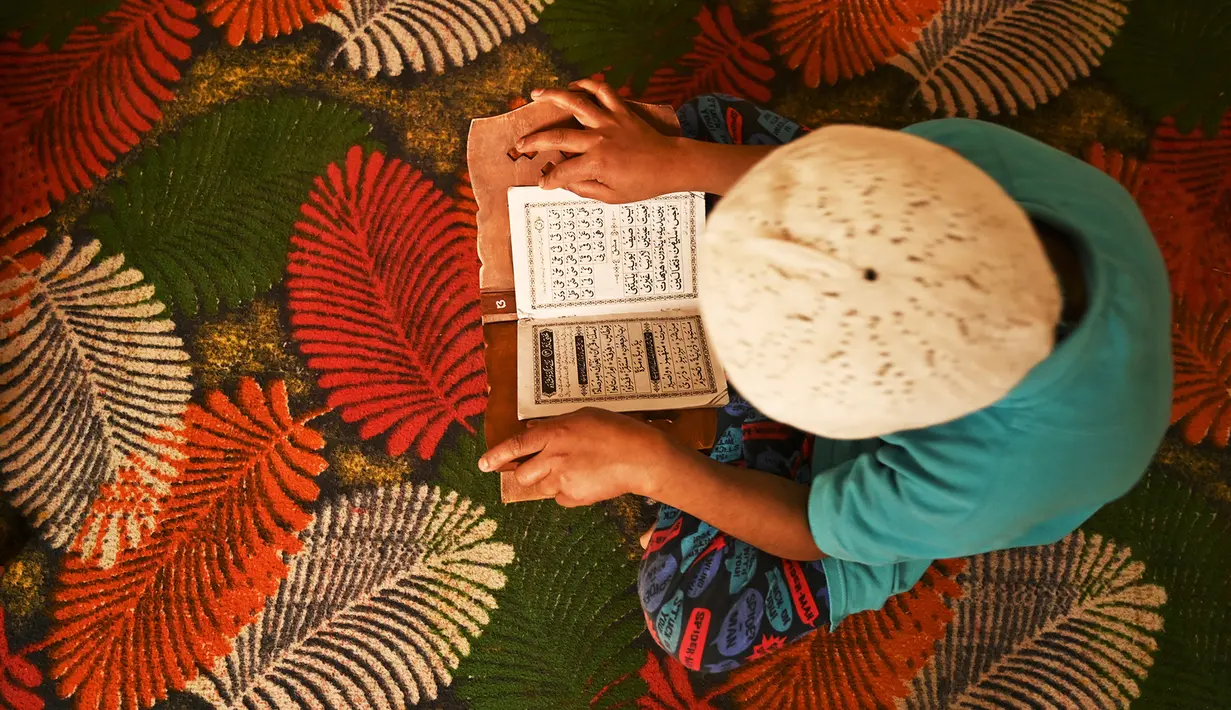 Seorang anak yatim Muslim mengenakan masker bertadarus sambil menjaga jarak sosial di dalam pusat panti asuhan selama bulan suci Ramadan di Srinagar (11/5/2020). (AFP/Tauseff Mustafa)