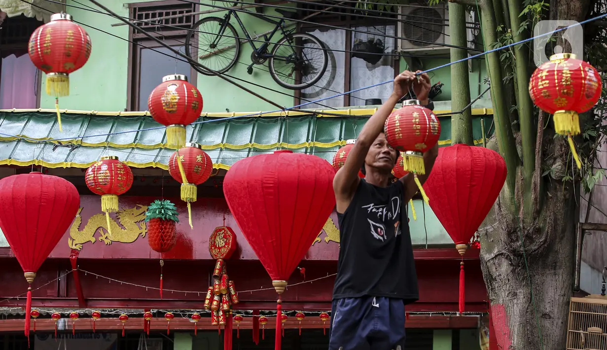 Warga menghias jalan dengan lampion di Kampung Limo, Depok, Jawa Barat, Rabu (26/1/2022). Kampung dengan sejumlah warga keturunan Tionghoa tersebut menyambut perayaan Tahun Baru Imlek 2022 dengan menghias gapura dan jalan dengan pernak-pernik Imlek. (Liputan6.com/Johan Tallo)