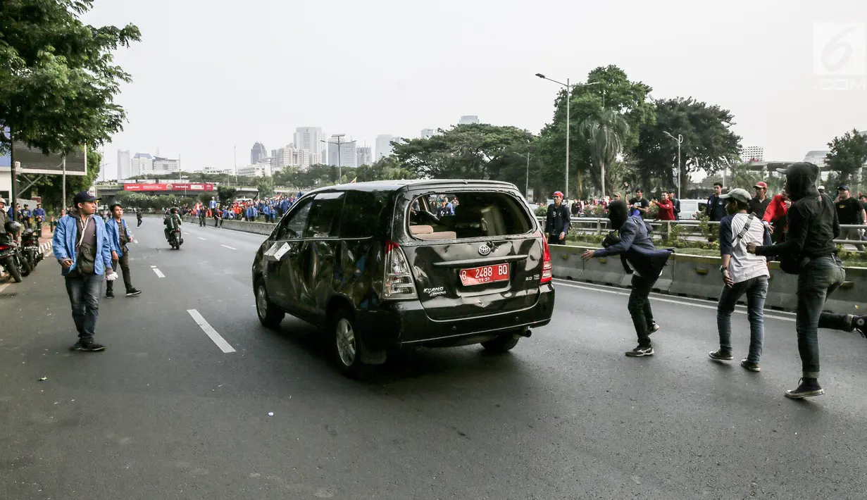 Mobil pelat nomor merah dilempari oleh massa aksi saat melintasi jalan tol seberang Gedung DPR/ MPR RI, Jakarta, Selasa (24/9/2019). Selain menutup ruas tol, kendaraan dinas pemerintah dan milik polisi jadi korban pelemparan dan perusakan oleh mahasiswa. (Liputan6.com/Faizal Fanani)