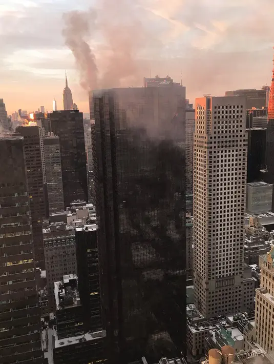 Asap membumbung dari bagian sudut atas gedung Trump Tower di New York, Senin (8/1). Petugas pemadam kebakaran New York City mengatakan api tersebut muncul dari sistem pemanas dan penyejuk udara gedung. (Jeff Levi via AP)