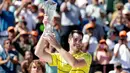 Petenis AS, John Isner memegang trofi seusai meraih gelar juara Miami Terbuka 2018 di Key Biscayne, Minggu (1/4). Pada laga final yang menegangkan tersebut, Isner sukses menaklukkan petenis Jerman Alexander Zverev 6-7, 6-4, 6-4. (AP/Lynne Sladky)