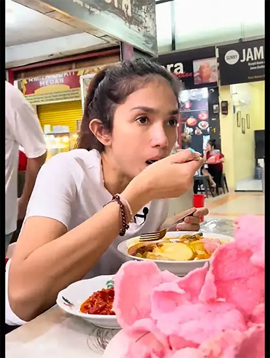 Potret perempuan lima orang anak itu saat makan di pasar tradisional. Ussy salah satu artis yang juga gemar ke pasar tradisional untuk belanja kebutuhan dapur. Dalam vlog tersebut, sebelum belanja, ia terlebih dulu berburu kuliner. [Youtube/Ussy Andhika Official]