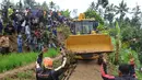 Warga memandu alat berat melalui jalan kecil menuju lokasi longsor di Dusun Cimapag, Sirnaresmi, Cisolok, Sukabumi, Jawa Barat, Selasa (1/1). Sebanyak 38 warga belum ditemukan dan masih dalam proses pencarian. (Merdeka.com/Arie Basuki)