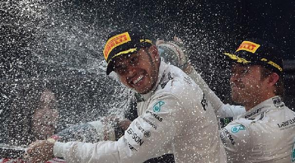 Nico Rosberg membalas menyemprotkan sampanye ke muka Lewis Hamilton