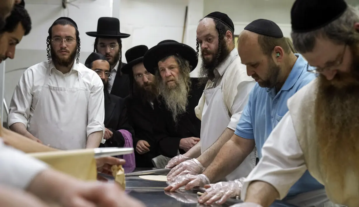 Yahudi Ultra-Ortodoks menyiapkan matzoh khusus di sebuah toko roti di Ashdod, Israel, 11 April 2022. Orang Yahudi dilarang makan makanan beragi selama liburan Paskah merayakan kisah alkitabiah tentang bangsa Israel saat melarikan diri dari perbudakan dan eksodus dari Mesir. (AP Photo/Tsafrir Abayov)