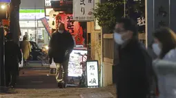 Orang-orang memakai masker untuk melindungi dari penyebaran virus corona berjalan di sepanjang jalan yang dipenuhi bar dan restoran di Tokyo, Rabu (19/1/2022). Tokyo dan puluhan daerah lain di Jepang akan menghadapi pembatasan COVID-19 baru yang berlaku efektif Jumat (21/1). (AP Photo/Koji Sasahara)