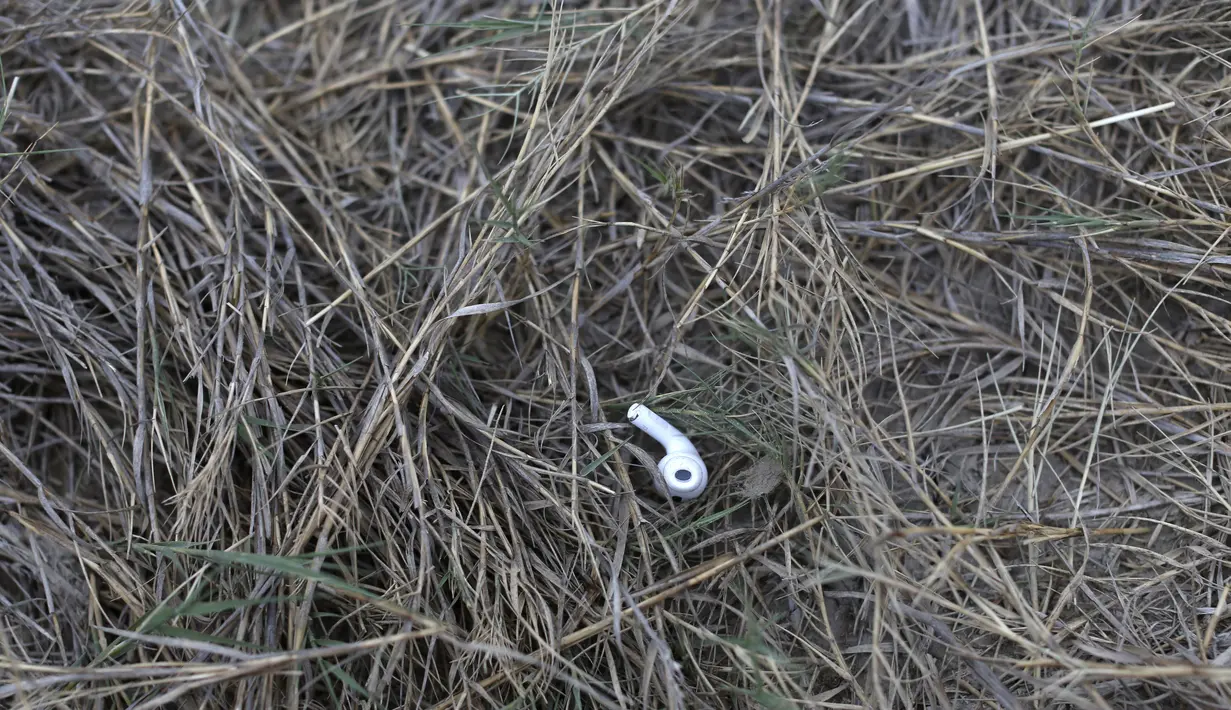Salah satu bagian dari headphone nirkabel terletak di tanah dekat tepi sungai Rio Grande di Roma, Texas, pada 28 Maret 2021. Saat kegelapan mulai terbenam di Rio Grande, aliran rakit yang membawa migran menyeberangi sungai ke tanah Amerika Serikat. (AP/Dario Lopez-Mills)