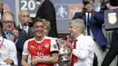 Pelatih Arsenal, Arsene Wenger memegang trofi Piala FA di Stadion Wembley, London, Sabtu (27/5). Arsenal mengalahkan Chelsea 2-1 dalam laga final Piala FA 2016-2017. (AP Photo)