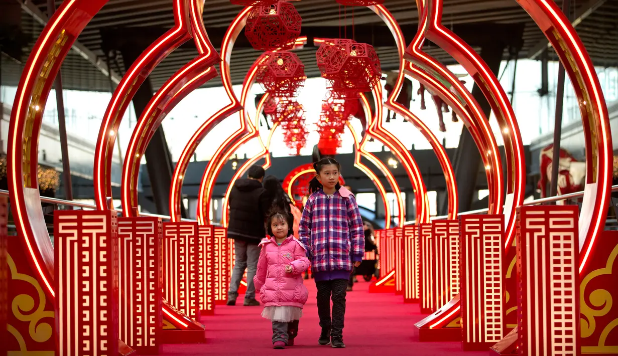 Dua orang anak melintas di sebuah jembatan bertema Imlek di sebuah pusat perbelanjaan kelas atas di Beijing (21/2). Jembatan berwarna merah yang bertema Imlek ini menjadi pusat perhatian dan tempat berfoto pengunjung. (AP Photo / Mark Schiefelbein)