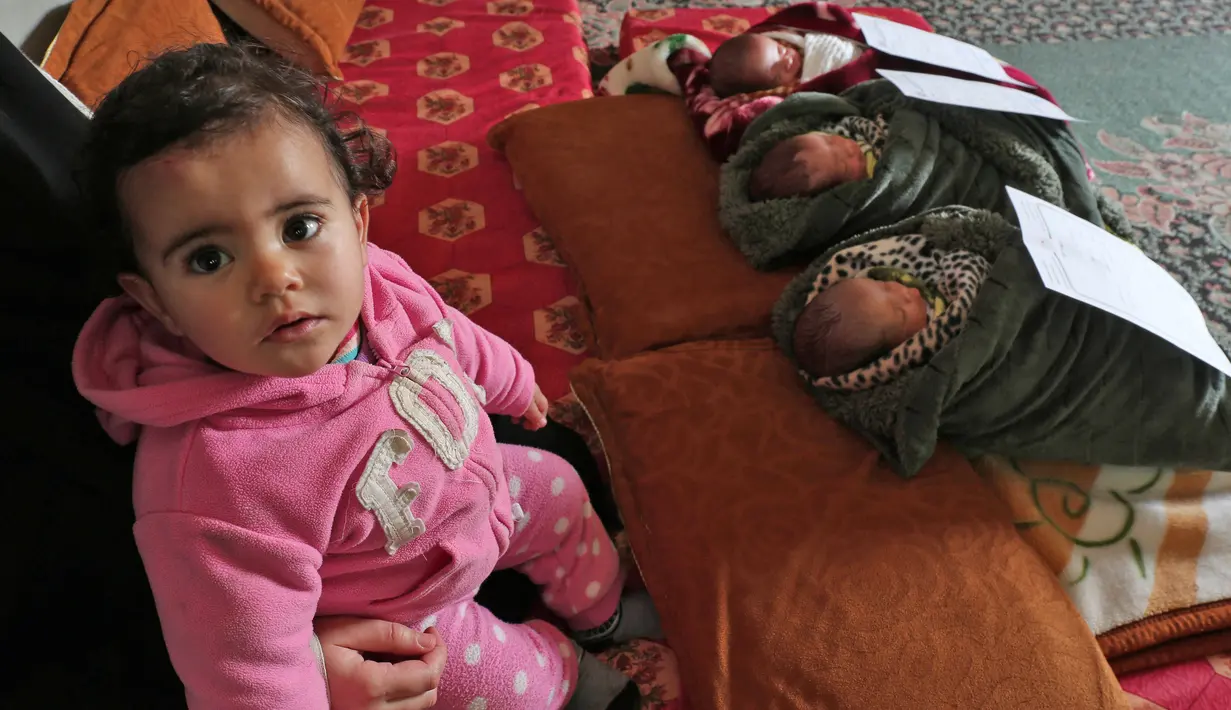 Bocah perempuan duduk dekat adik kembarnya yang diberinama Jerusalem, Capital dan Palestine di Khan Yunis, Jalur Gaza, Jumat (2/2). Pasangan Nidal dan Islam Al-Saiqli memberi nama unik kepada tiga bayi kembar mereka yang baru lahir. (SAID KHATIB/AFP)