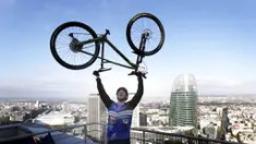 Pembalap sepeda asal Prancis, Aurelien Fontenoy, melakukan selebrasi usai berhasil mendaki 768 anak tangga dari 33 lantai gedung Trinity Tower di distrik La Defense, Paris, (17/1/2021). (AP/Christophe Ena)