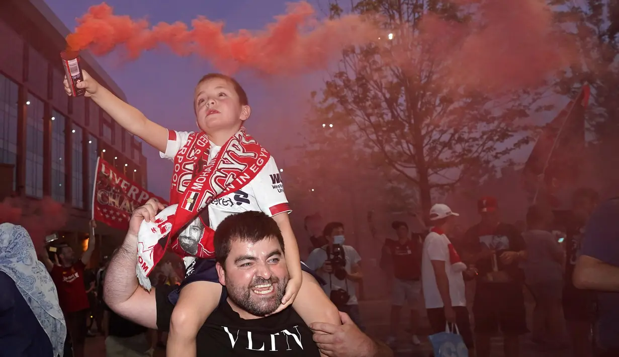 Pendukung Liverpool merayakan gelar juara Liga Premier di luar Stadion Anfield, Kamis (25/6/2020). Trofi juara Liga Primer musim 2019-2020 tersebut dimenangkan Liverpool setelah Manchester City takluk 1-2 dari Chelsea di Stamford Bridge. (AP Photo/Jon Super)