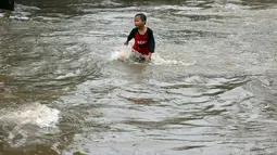Seorang anak asyik bermain banjir yang merendam kawasan Benhil RT 03 RW 05, Jakarta Pusat, Selasa (21/1). Hujan deras yang mengguyur sejak Selasa dinihari mengakibatkan kawasan tersebut mengalami banjir. (Liputan6.com/Johan Tallo)