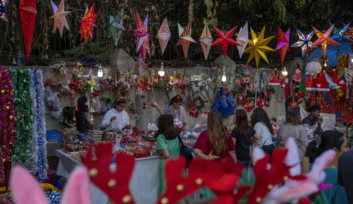 Orang-orang berbelanja suvenir Natal dari pedagang pinggir jalan di Mumbai, India, Selasa (20/12/2022). Jelang puncak perayaan Natal, warga Mumbai mulai ramai berburu ornamen dan aksesoris Natal untuk menyambut dan memeriahkan perayaan untuk umat kristiani tersebut. (AP Photo/Rafiq Maqbool)