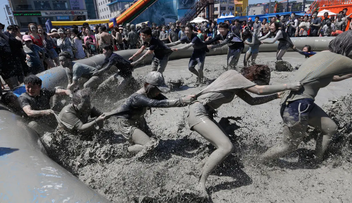 Sejumlah orang bermain di kolam lumpur selama Festival Lumpur Boryeong di Pantai Daecheon di Boryeong, Korea Selatan, (14/7). Festival lumpur tahunan ke-21 ini menampilkan gulat lumpur. (AP Photo / Ahn Young-joon)