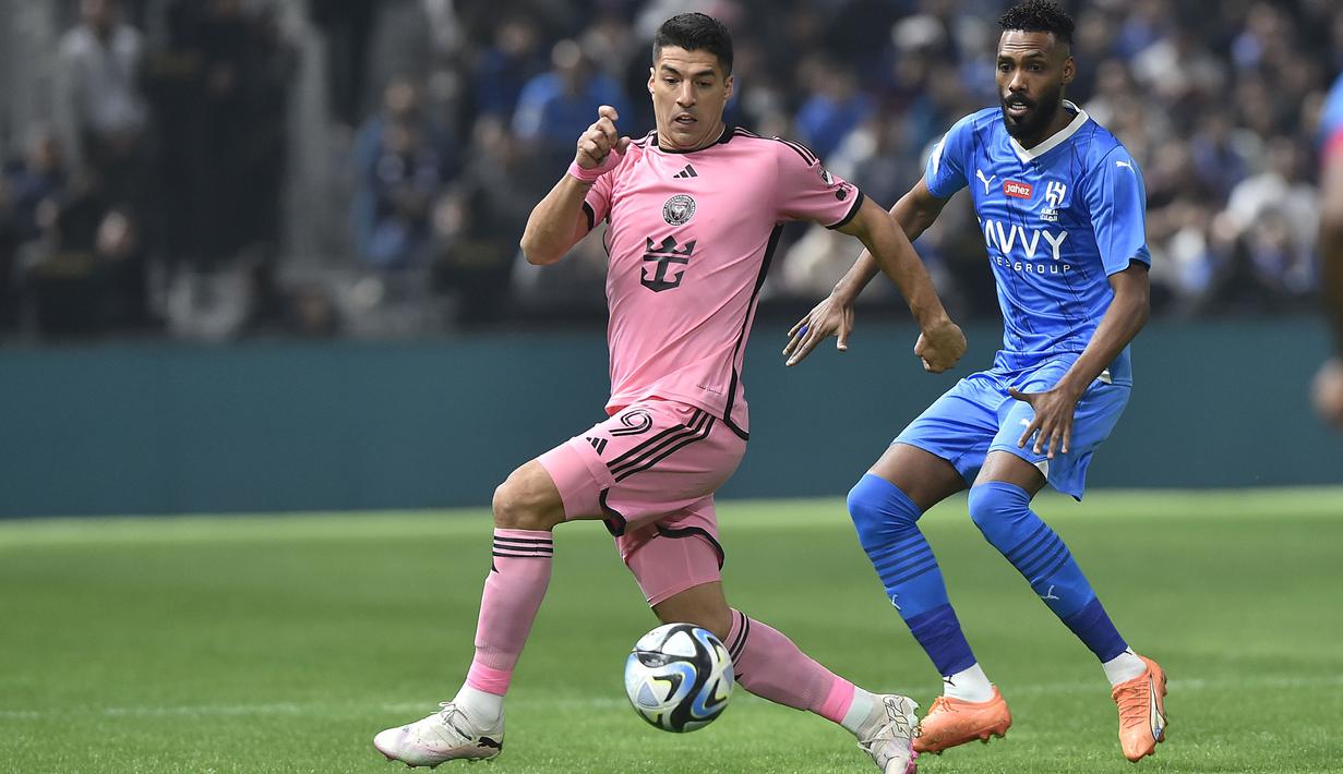 Pemain Inter Miami, Luis Suares (kiri) berebut bola dengan pemain Al-Hilal saat laga persahabatan yang berlangsung di Kingdom Arena Stadium, Riyadh, Arab Saudi, Selasa (30/01/2024) WIB. Keputusan golnya tersebut berubah setelah meneninjau VAR. Bola yang awalnya dikira merupakan umpan dari Julian Gressel ternyata tersentuh kaki pemain Al-Hilal, Mohammed Jahfali. (AP Photo)