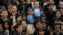 Sejumlah pelayat memegang foto Raja Bhumibol Adulyadej saat berkumpul di luar Grand Palace sambil menyanyikan rekaman lagu kerajaan, di Bangkok, Thailand, (22/10). Malamnya para pelayat akan menyalakan lilin dan menyanyikan lagu. (REUTERS/Jorge Silva)