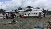 Warga berusaha menggali lumpur yang menimbun helikopter Mi-17 milik BNPB pasca banjir bandang di Kabupaten Sentani, Jayapura, (17/3). Banjir bandang Sentani menewaskan 70 orang dan puluhan luka-luka. (AFP/Netty Dharma Somba)