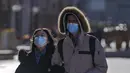 Sepasang suami istri mengenakan masker untuk membantu mengekang penyebaran virus corona berjalan melalui distrik perbelanjaan Wangfujing di Beijing, Minggu (12/12/2021).  (AP Photo/Andy Wong)